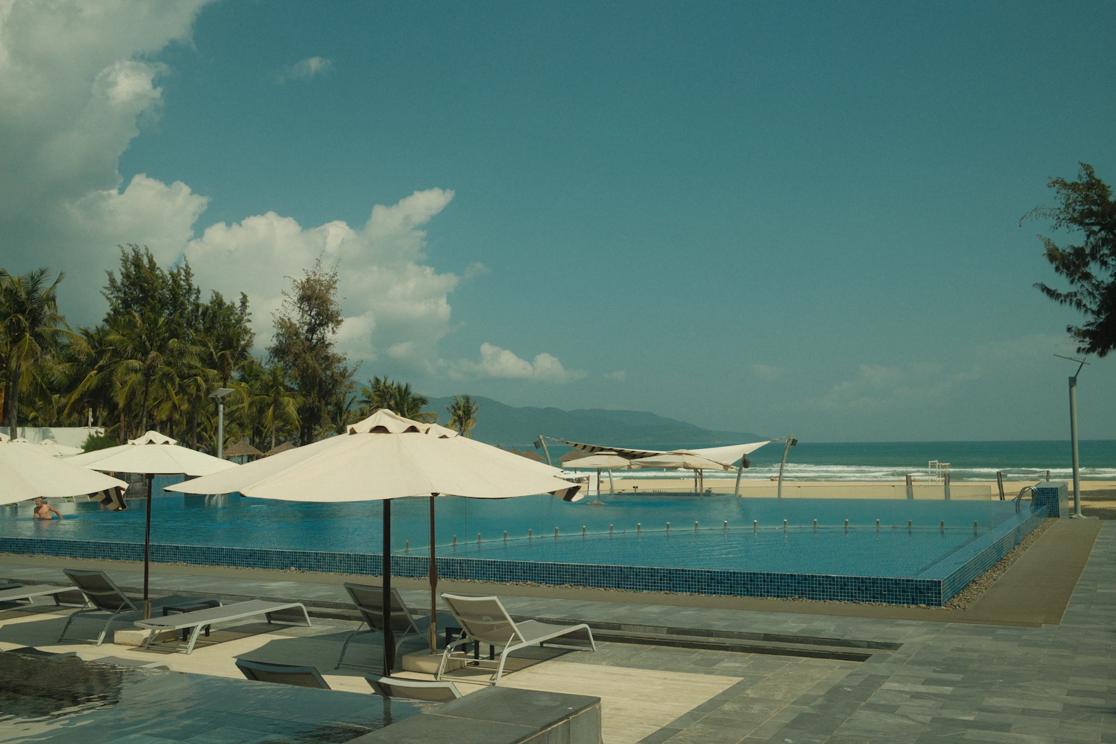 Pool, solstolar och parasoll vid havet